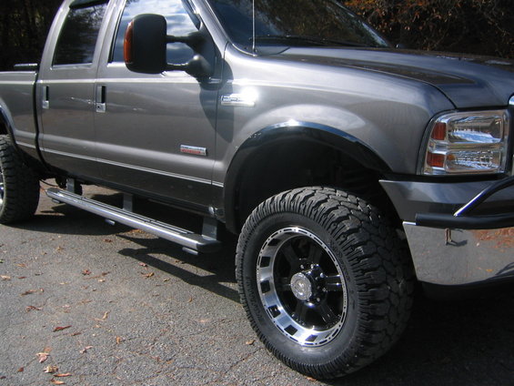 Gray pickup truck with custom wheels and tires, 3/4 front view