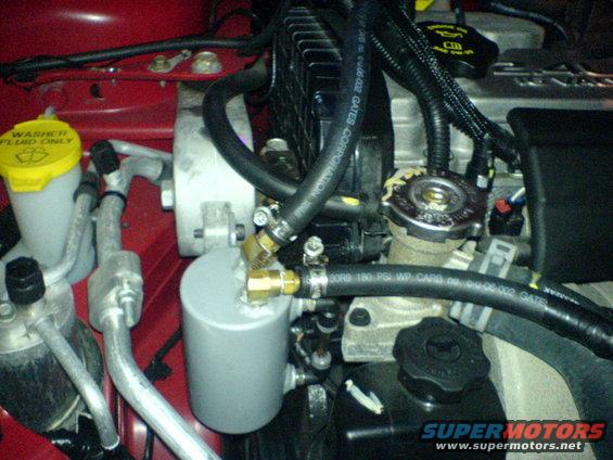 Engine bay with red paint, silver canister, and black hoses. Washer fluid cap is yellow