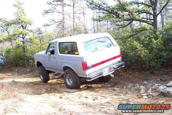 White 1987 Ford Bronco flexing on a dirt trail
