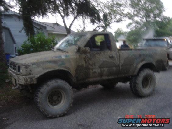 Mud-covered 1992 Toyota Tacoma pickup truck with lifted suspension and off-road tires parked on a street
