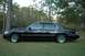 1999 Lincoln Town Car - Side profile of a black sedan parked on grass with trees in the background. The body style indicates a late 1990s model.