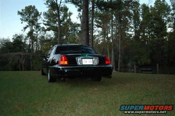 black sedan parked on grass, trees in background