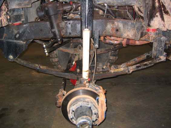 Vehicle front suspension with leaf springs, shock absorber, brake rotor, and steering linkage