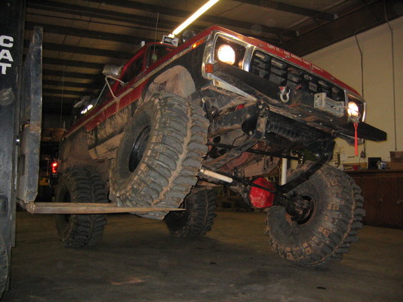 1979 Ford Bronco front end lifted by forklift, showing large off-road tires and suspension