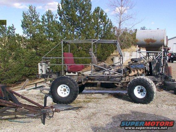 Custom buggy frame with red seats and engine exposed, parked outdoors