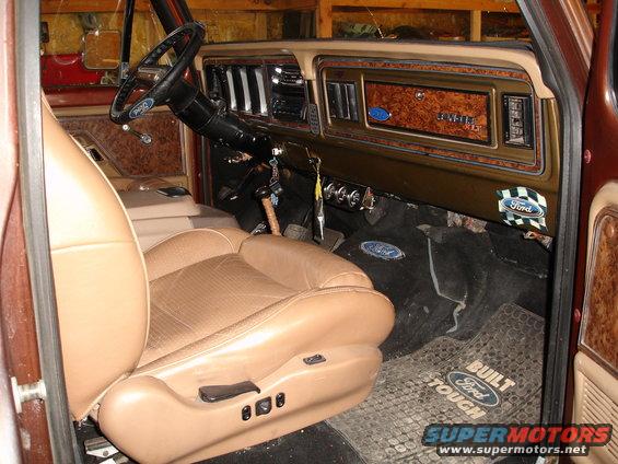 1979 Ford F-150 interior with tan seats, wood grain dash, and Ford floor mats