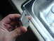 2005 Dodge SRT-4 - A person holds a metal component with two bolt holes, possibly for a vehicle repair.