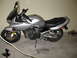2003 Suzuki Bandit S - A silver 2003 Suzuki Bandit S motorcycle is parked indoors, showing its side profile with a black seat and windshield.
