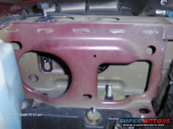 Close-up of a red metal bracket in a vehicle's engine bay. Date stamp 11/22/2006