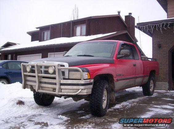 Red pickup truck with a large silver bull bar on the front, parked in a snowy driveway