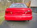 1995 Ford Taurus - Rear view of a red 1995 Ford Taurus, showing its distinctive taillights and spoiler.