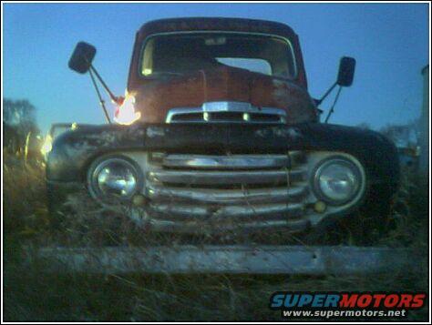 Rusty red truck front end with chrome grille and round headlights