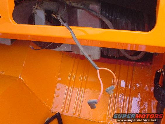 Orange interior of a vehicle with exposed wiring and connectors. Ribbed floor visible