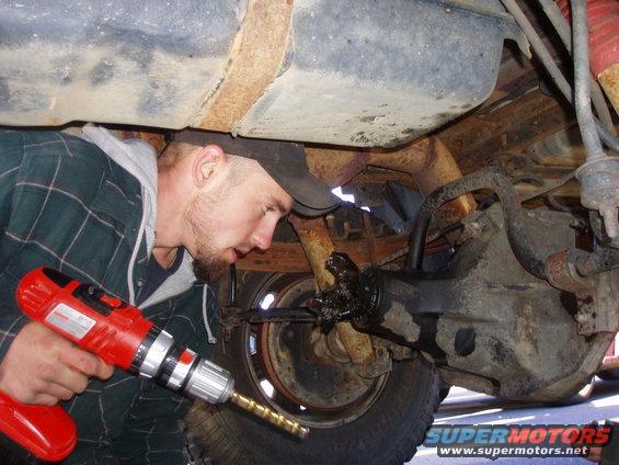 Guy using a drill on the rear axle of a truck