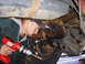1989 Ford F-350 - A person is working on the rear axle of a vehicle with a drill.