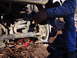 1989 Ford F-350 - A person works on the suspension and brake components of a vehicle, with the ground and debris visible below.