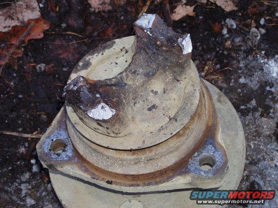 Close-up of a broken metal part with two mounting holes. It looks like part of a vehicle's drivetrain