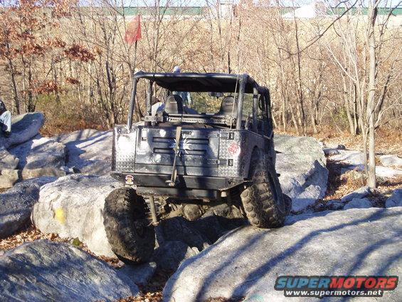 Black off-road vehicle with roll cage navigating large rocks