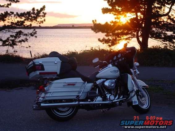White touring motorcycle parked by a lake at sunset