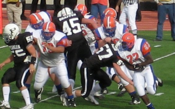 Football players in black and white uniforms on a green field during a game