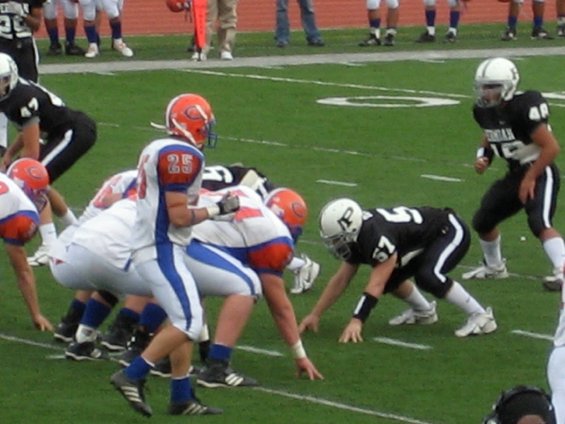 American football players in uniform on a green field, lined up for a play