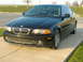 2001 BMW 3 Series - A black BMW 3 Series coupe is parked on a concrete driveway, showing its distinctive grille and headlights.