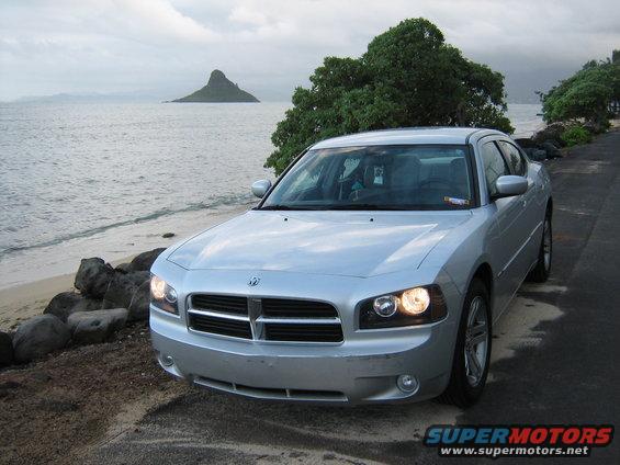 Silver 2006 Dodge Charger parked on a road next to a beach with a distinctive island in the background
