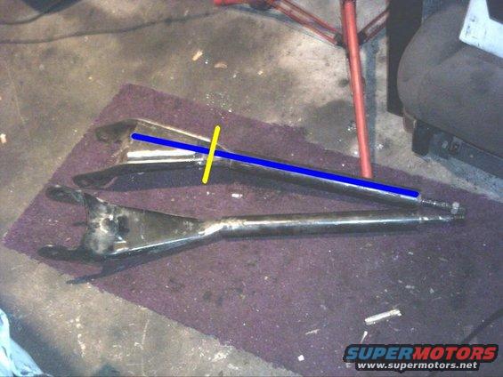Two metal automotive suspension control arms laid out on a purple mat