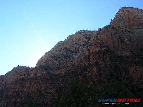 Mountain range under a clear blue sky with a faint contrail