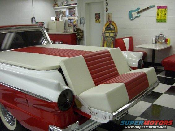 1957 Ford Ranchero with custom red and white bench seat in bed, parked in a retro diner-themed garage