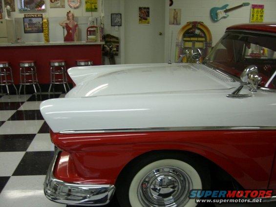 Two-tone red and white 1957 Ford Fairlane, side view, showing fender and hood