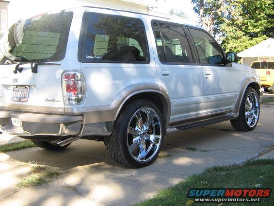 White 2001 Ford Explorer SUV with chrome rims and tan trim, viewed from the rear three-quarter angle