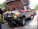 1996 Ford F-250 - A red and gray Ford Bronco is parked with its hood open, while another red truck is visible behind it.