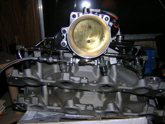 Close-up of a throttle body attached to an aluminum intake manifold with fuel injectors