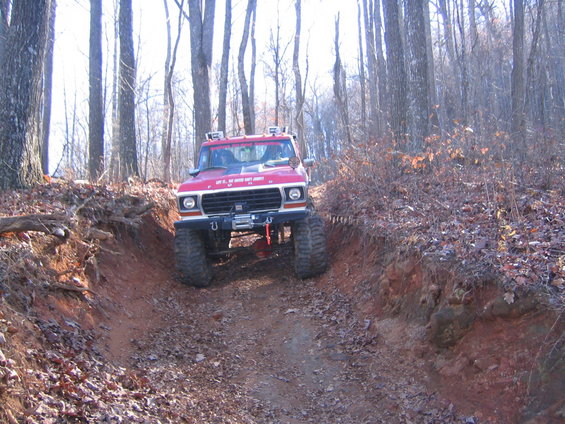 Red 1979 Ford Bronco on a dirt trail, front view