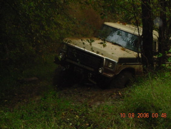 Tan off-road vehicle stuck in mud, front 3/4 view
