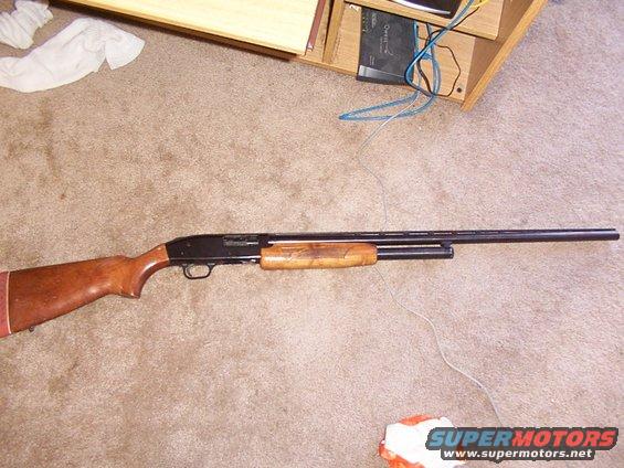 Wooden shotgun with a red butt pad lying on a carpeted floor