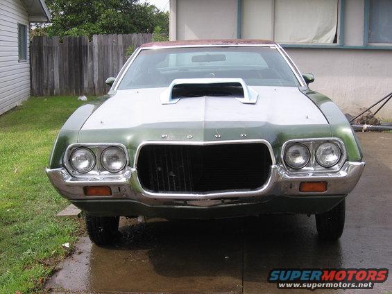 Green 1972 Ford Ranchero with a white hood scoop and chrome bumper, viewed from the front