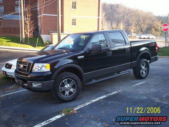 Black Ford F-150 SuperCrew pickup truck parked next to a white Ford Crown Victoria