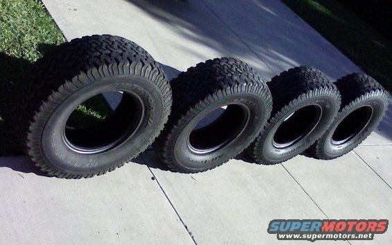 Four off-road tires lined up on a concrete surface