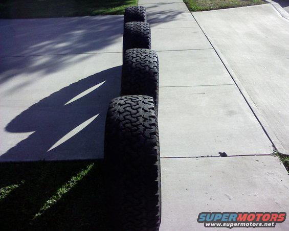 four off-road tires lined up on a sidewalk