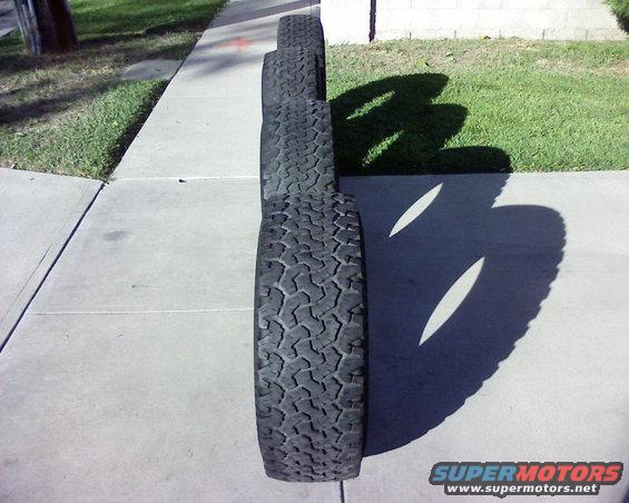Four off-road tires lined up on a sidewalk