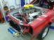 1990 Ford Mustang - Engine bay of a 1990 Ford Mustang, a dual carburetor setup and prominent red body panels.