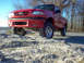 2001 Mazda B3000 - This red 2001 Mazda B3000 pickup truck is shown from a low angle, highlighting its lifted suspension and front grille.