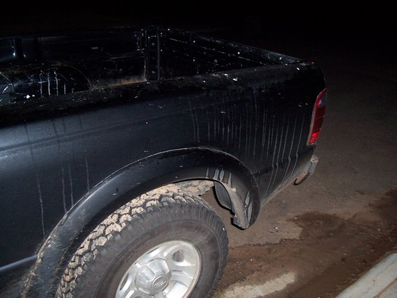 Black 2003 Ford Ranger pickup truck rear quarter panel and bed, muddy tire, dirty exterior