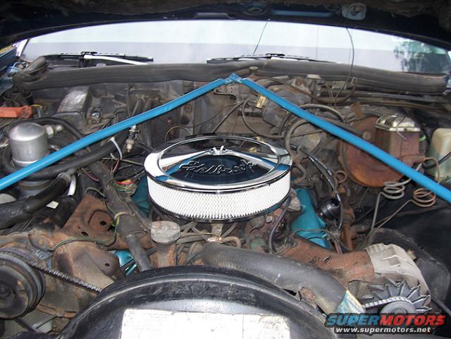 Engine bay showing a V8 engine with a chrome Edelbrock air cleaner and blue strut tower brace
