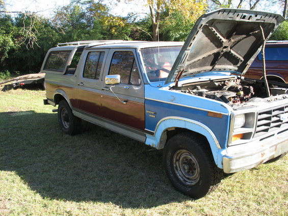 Gray and brown Ford Bronco with hood open, showing engine. Blue front clip
