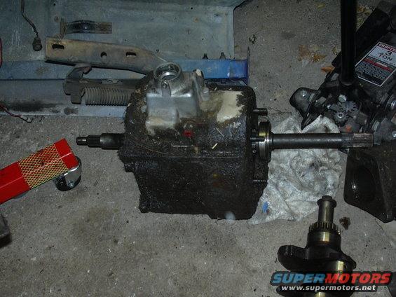 Transmission case with driveshaft attached, and a separate crankshaft on a garage floor