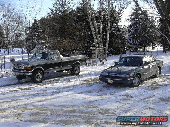 1995 Ford F-Series truck and a dark blue Ford Crown Victoria parked in snow