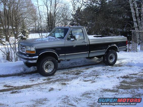 Two-tone gray and black Ford F-250 pickup truck in snow, 3/4 front view